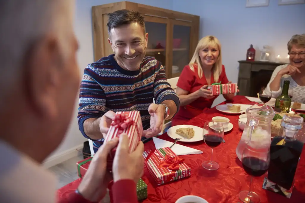 Uśmiechnięty mężczyzna wręcza prezent starszemu mężczyźnie w domu