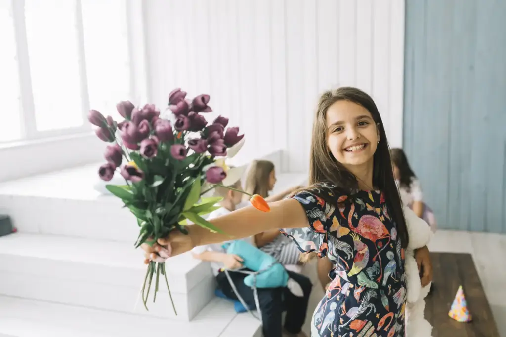 Uśmiechnięta dziewczynka pokazuje bukiet kwiatów na przyjęciu
